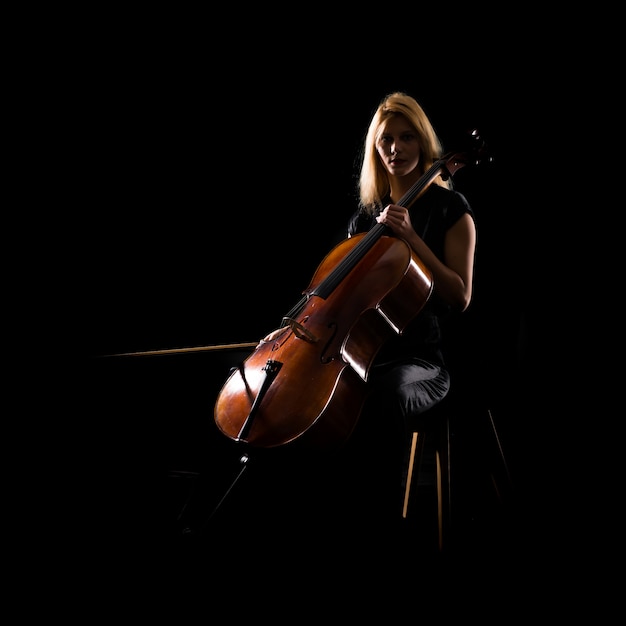 Junges Mädchen, das das Cello auf lokalisiertem schwarzem Hintergrund spielt