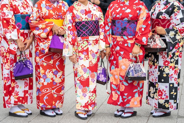 Junges Mädchen, das den japanischen Kimono steht vor Sensoji-Tempel trägt