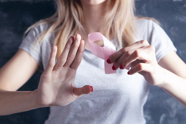 Junges Mädchen, das eine rosa Schleife hält und Halt zeigt