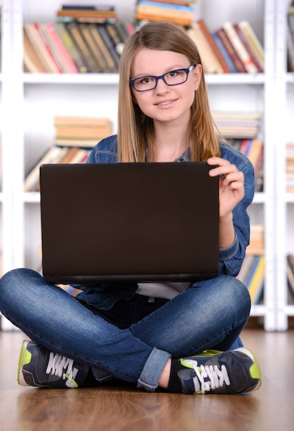 Junges Mädchen, das einen Laptop in der Bibliothek verwendet.