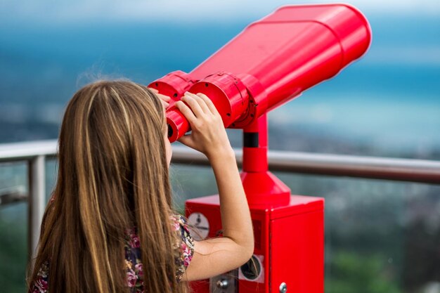 Junges Mädchen, das einen Turmbetrachter verwendet, um das Panorama der Stadt zu betrachten