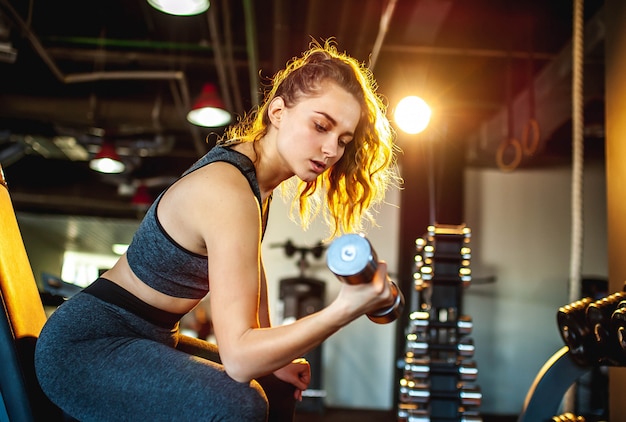 Junges Mädchen, das Gewichte im Fitnessstudio hebt