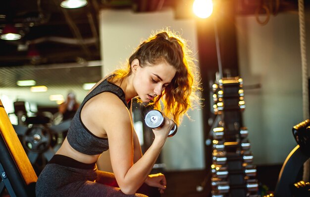 Junges Mädchen, das Gewichte im Fitnessstudio hebt