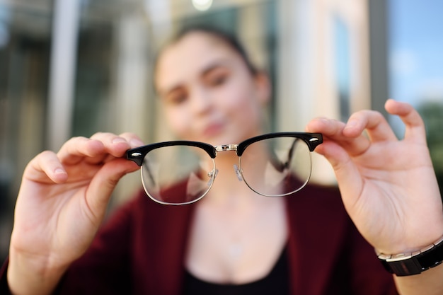 Junges Mädchen, das Glasnahaufnahme hält. Optik, blzorukost, Weitsichtigkeit, Astigmatismus.