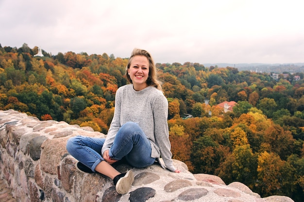 Junges Mädchen, das im Herbstwald spazieren geht. Schöner Park mit trockenen gelben und roten Blättern und bunten Bäumen.