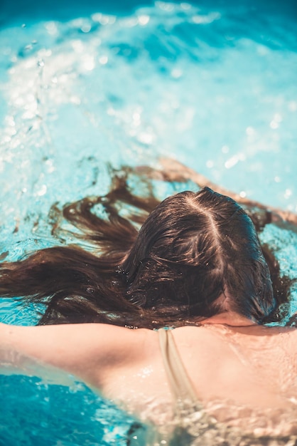 Junges Mädchen, das in der Rückansicht der Poolnahaufnahme schwimmt