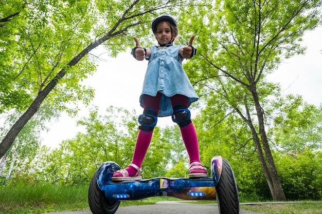 Junges Mädchen, das in einem Stadtpark auf Gyroscooter reitet Sommerunterhaltung in der Natur Elektroroller ist ein modernes, umweltfreundliches Transportmittel, selbstausgleichender Roller, gesunder Lebensstil