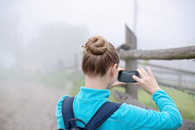 Junges Mädchen, das mit dem Smartphone ein Foto von einem wilden Ort macht