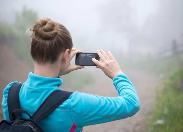 Junges Mädchen, das mit dem Smartphone ein Foto von einem wilden Ort macht