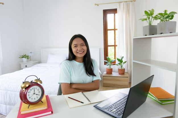 Junges Mädchen, das mit Laptop im Schlafzimmer lernt, lernt zu Hause