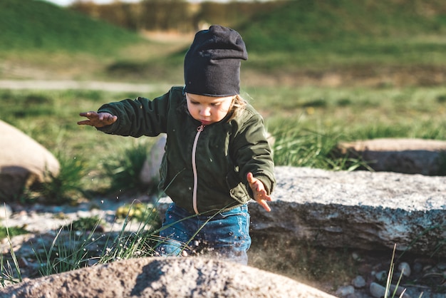 Junges Mädchen, das mit Sand auf dem Felsen spielt