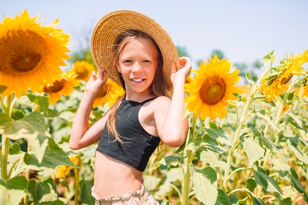 Junges Mädchen, das Natur auf dem Feld der Sonnenblumen genießt.