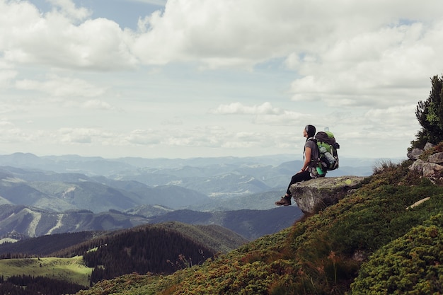 Junges Mädchen, das oben auf Klippe in den Bergen steht, die Ansicht der Natur genießen