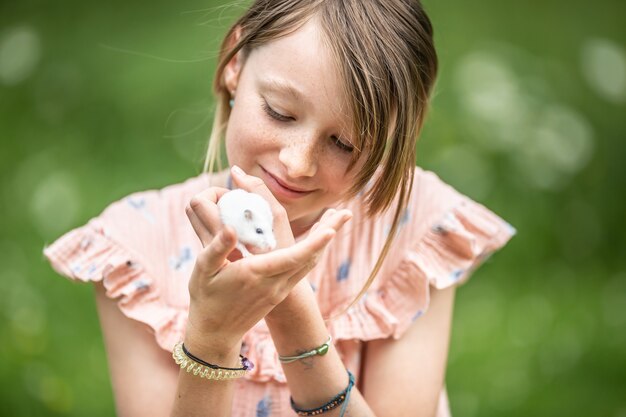 Junges Mädchen, das sich um eine kleine Maus kümmert.