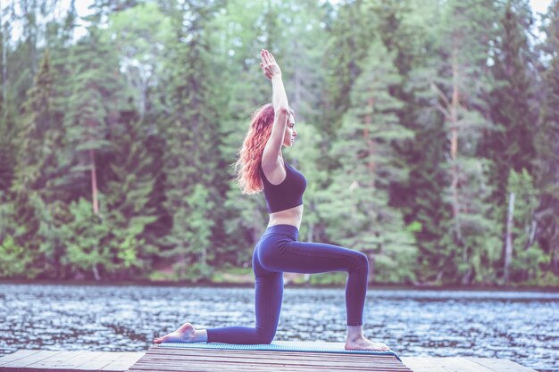 Junges Mädchen, das Yoga in der Natur am See praktiziert Weibliches Glück Konzept des gesunden Lebens und des natürlichen Gleichgewichts