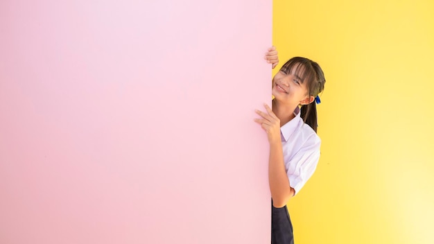 Junges Mädchen des glücklichen Studenten mit rosa und gelbem Hintergrund.