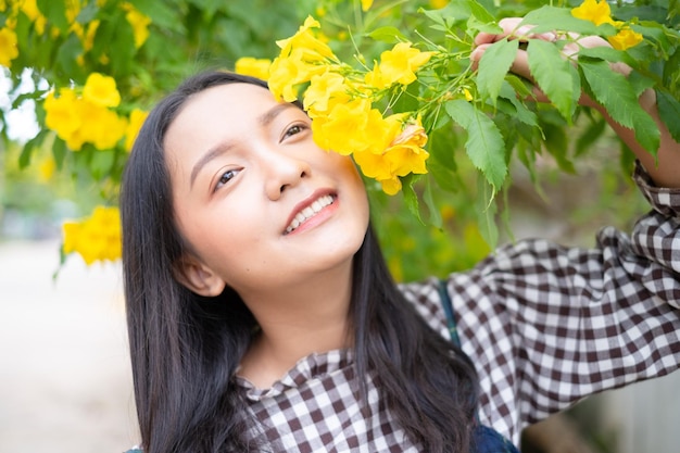 Junges Mädchen des Porträts mit gelben Blumen Asiatisches Mädchen