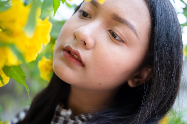 Junges Mädchen des Porträts mit gelben Blumen Asiatisches Mädchen