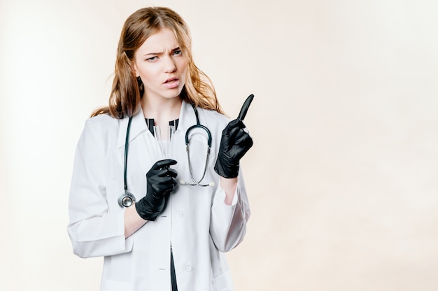Junges Mädchen ein Doktor auf einem hellen Hintergrund in den schwarzen Handschuhen