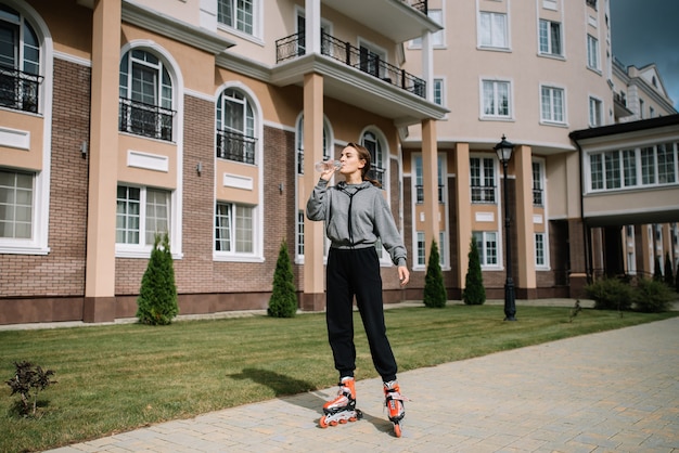 Foto junges mädchen fährt rollschuhe und trinkt sauberes wasser