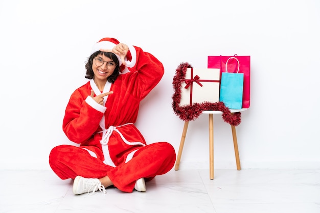 Junges Mädchen feiert Weihnachten auf dem Boden sitzend isoliert auf weißem bakcground Fokussierung Gesicht. Rahmensymbol