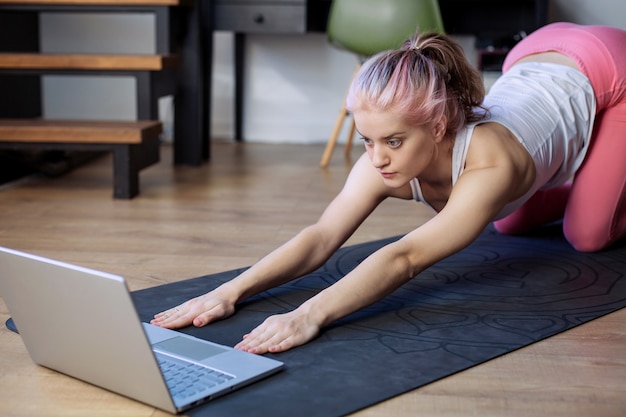 junges Mädchen geht Yoga-Sport online zu Hause. Aktive Lebensstilübung im Gesundheitswesen. Laptop-Programmtrainer Fernunterricht Workout Wellness