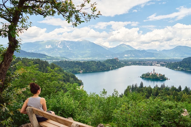 Junges Mädchen genießt die atemberaubende Aussicht am Bleder See, Slowenien. Seitenansicht.