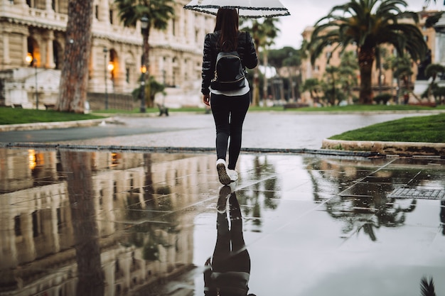 Junges Mädchen hält den Regenschirm, sie reflektiert im Wasser