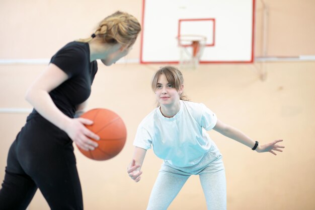Foto junges mädchen im fitnessstudio, das basketball spielt