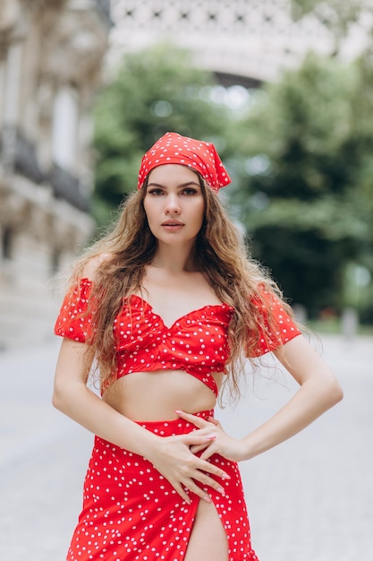 Junges Mädchen im roten Kleid in der Nähe des Eiffelturms in Paris am sonnigen Sommertag