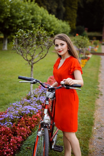 Junges Mädchen im roten Kleid mit Retro-Fahrrad im Park