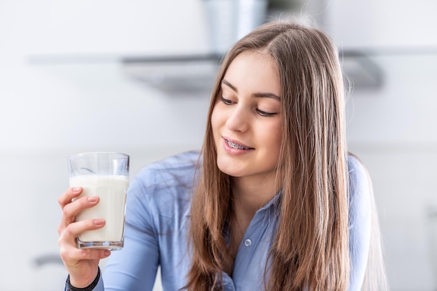 Junges Mädchen im Teenageralter mit Zahnspangen, das eine Tasse mit Milch hält