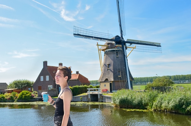 Junges Mädchen im Urlaub in Holland mit Blick auf die holländische Windmühle vom Lastkahn in der Kanalkreuzfahrt