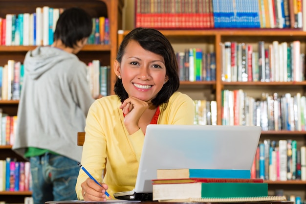 Junges Mädchen in der Bibliothek mit Laptop