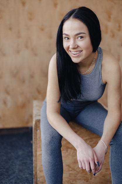 Junges Mädchen in der Sportbekleidung in einer Turnhalle in einem einfachen Hintergrund, ein Thema der Fitness, eines Crossfit und des Sports