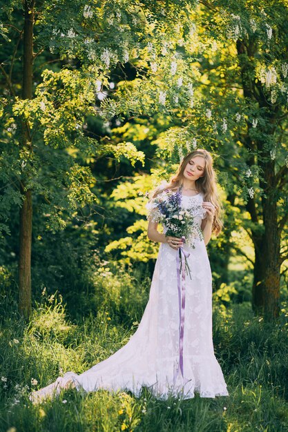 Junges Mädchen in einem weißen Kleid in der Wiese. Frau in einem schönen langen Kleid, das im Garten aufwirft
