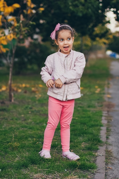 Junges Mädchen in einer rosa Jacke und in den rosa Leggings im Park.