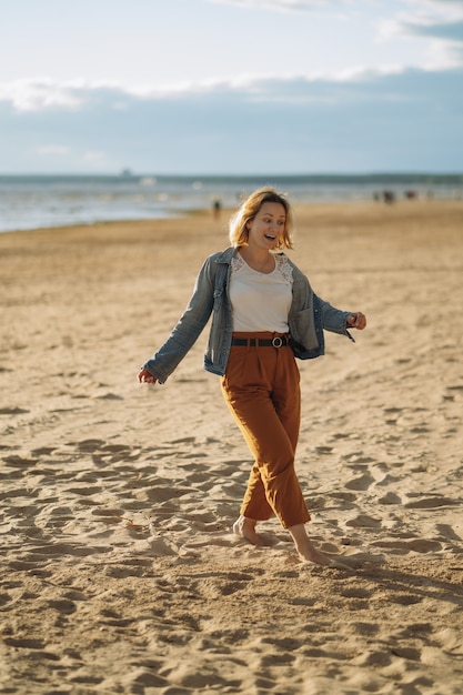 junges Mädchen in Jeansjacke genießt die Sonne am Strand am Sommerabend