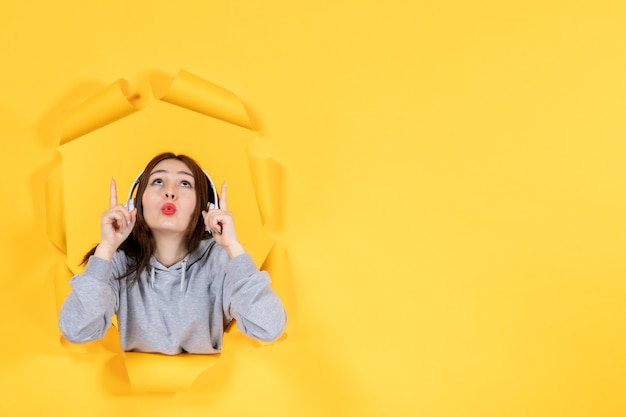 junges Mädchen in Kopfhörern auf gelbem Papier Hintergrundmusik Audio-Ultraschallton