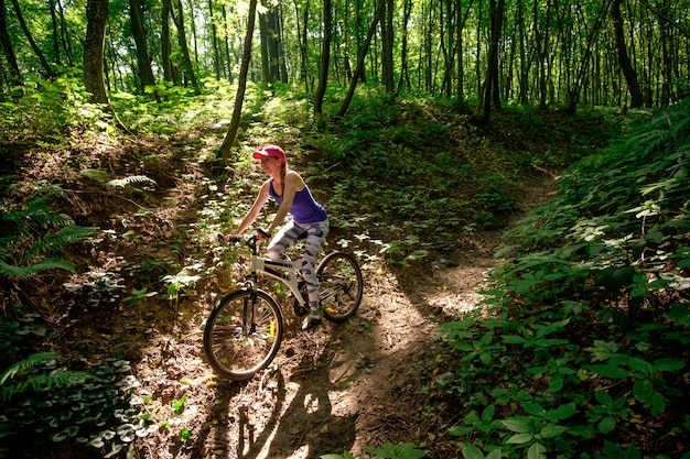 Junges Mädchen in Sportkleidung mit Fahrradfahren im Wald im Sommer