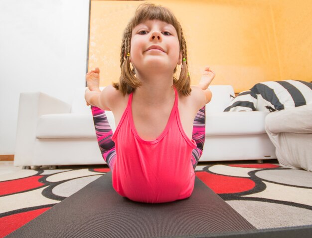 Junges Mädchen macht Yoga-Übungen am Teppich zu Hause