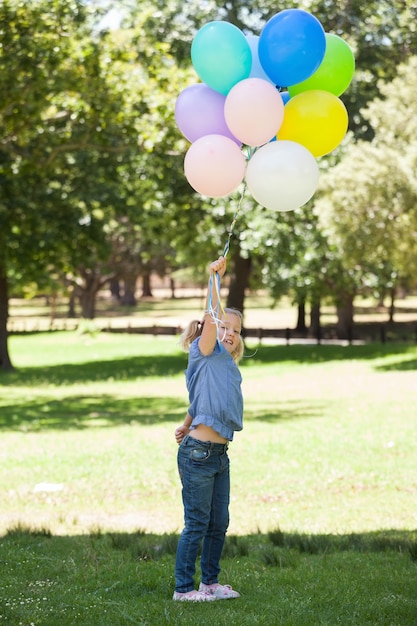 Junges Mädchen mit bunten Ballonen im Park