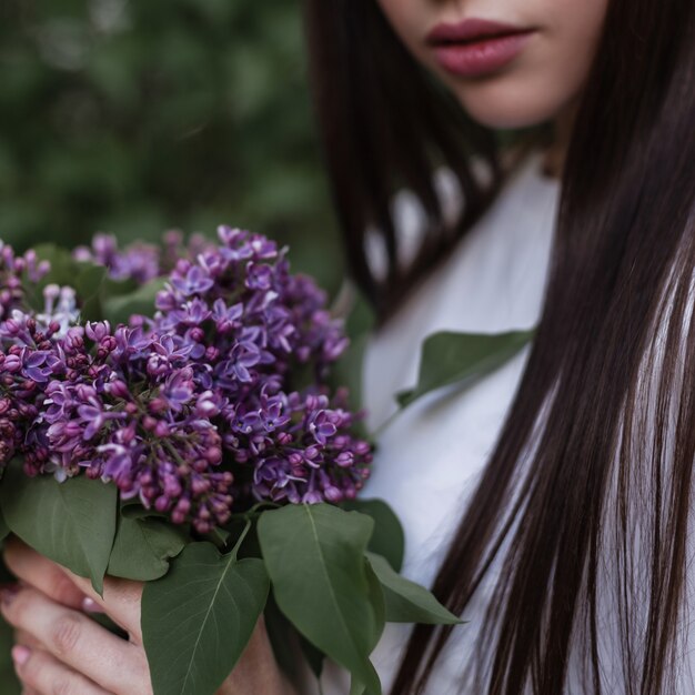 Junges Mädchen mit einem Frühlingsstrauß aus lila lila Blumen