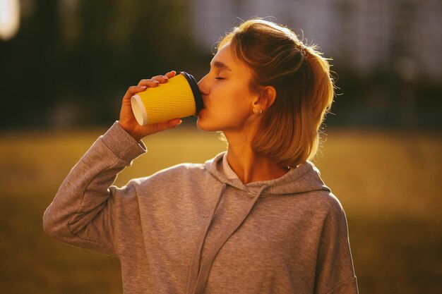 junges Mädchen mit einem Kaffee Mädchen trinkt Lat aus einem Pappbecher auf der Straße Vintage-Fotoverarbeitung