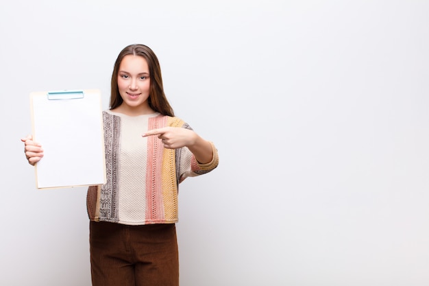 Junges Mädchen mit einem Papierblatt gegen weiße Wand