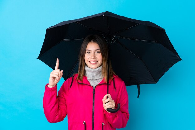 Junges Mädchen mit einem Regenschirm über blauer Wand