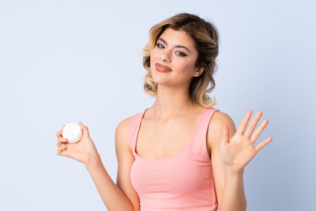 Junges Mädchen mit Feuchtigkeitscreme, die mit Hand salutiert