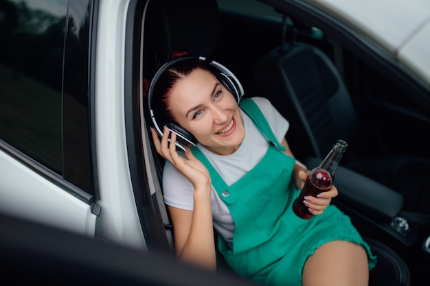 Junges Mädchen mit Kopfhörern, die Musik neben dem Auto hören