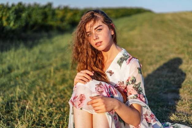 Junges Mädchen mit langen lockigen Haaren und Sommersprossen, mit Make-up und grünen Augen