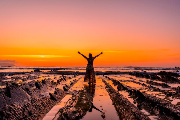 Foto junges mädchen mit offenen armen im wasser an den felsen